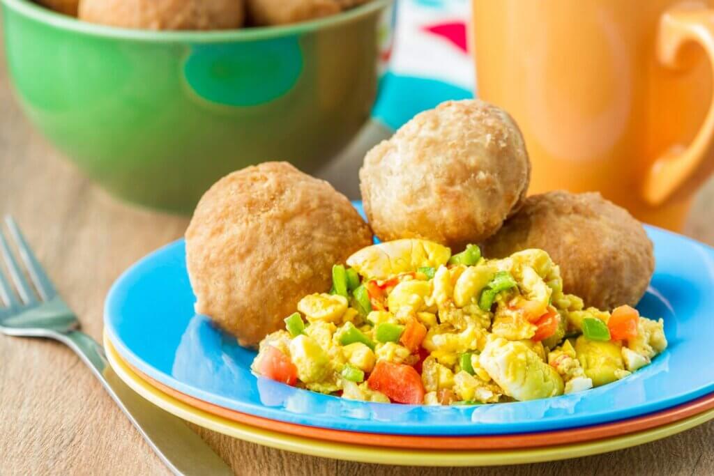 A brightly-coloured blue plate with ackee and saltfish, as well as a side of dumplings.